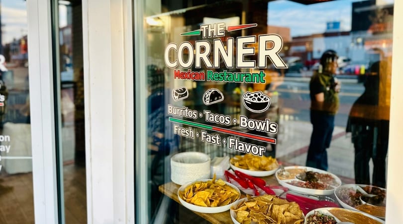 The Corner Mexican Restaurant storefront window with menu items and tortilla chips on display.